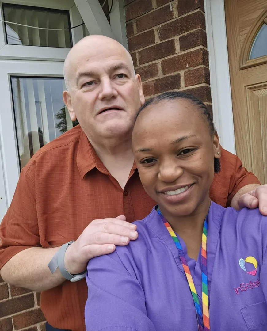 Astar Homecare carer proudly holding her staff ID badge with a big smile in a coffee shop.