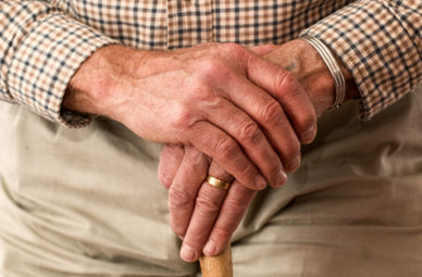 Elderly mans hands resting on walking stick