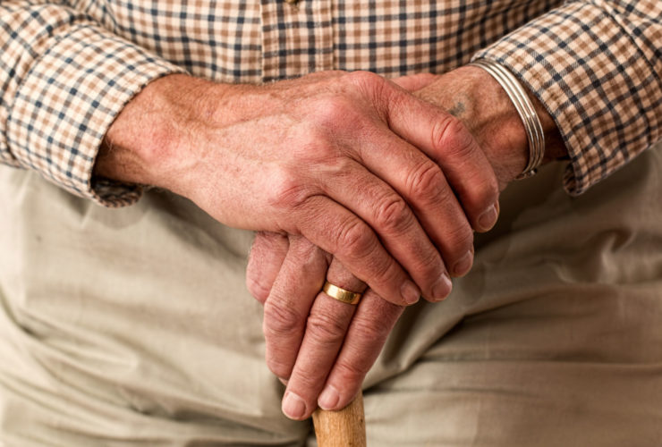Elderly mans hands resting on walking stick